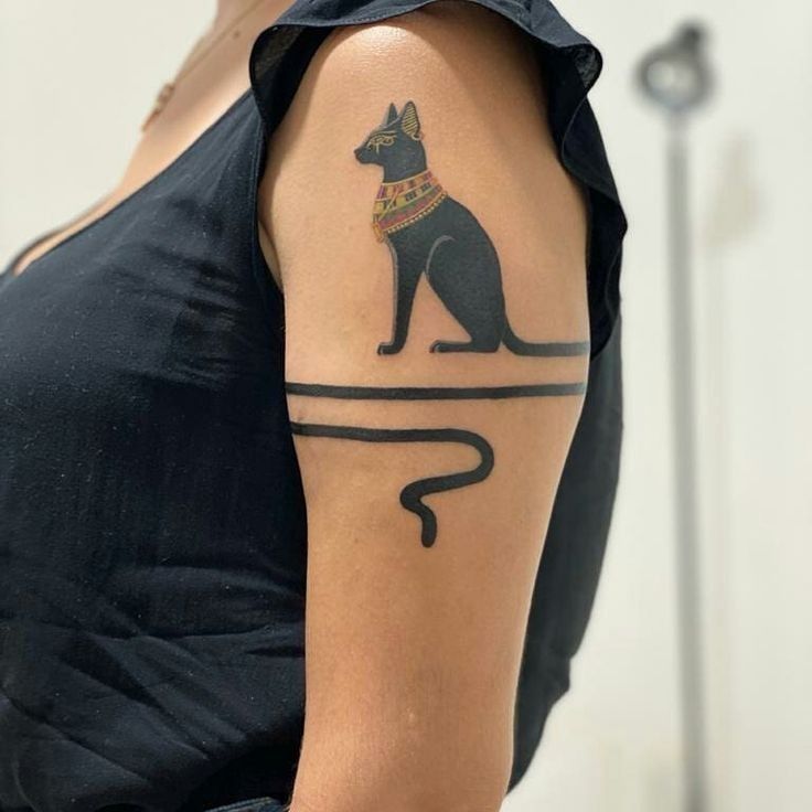 a woman's arm with an egyptian dog tattoo on the left side of her body