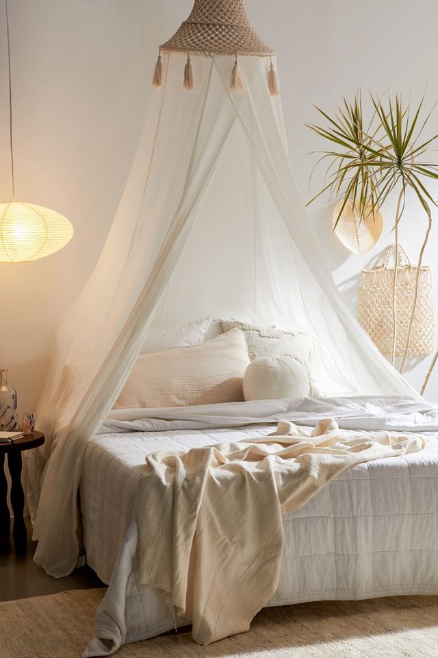 a bed with a white canopy over it and some plants on the wall next to it