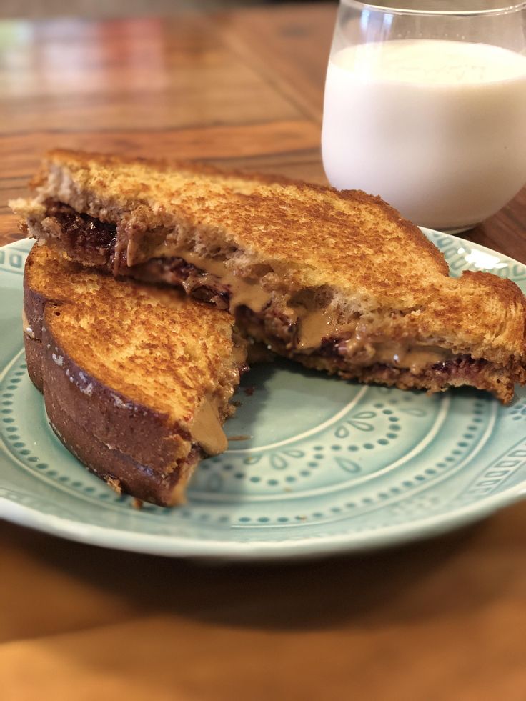 a sandwich cut in half on a plate next to a glass of milk