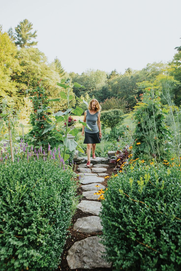 a woman walking down a stone path through a garden