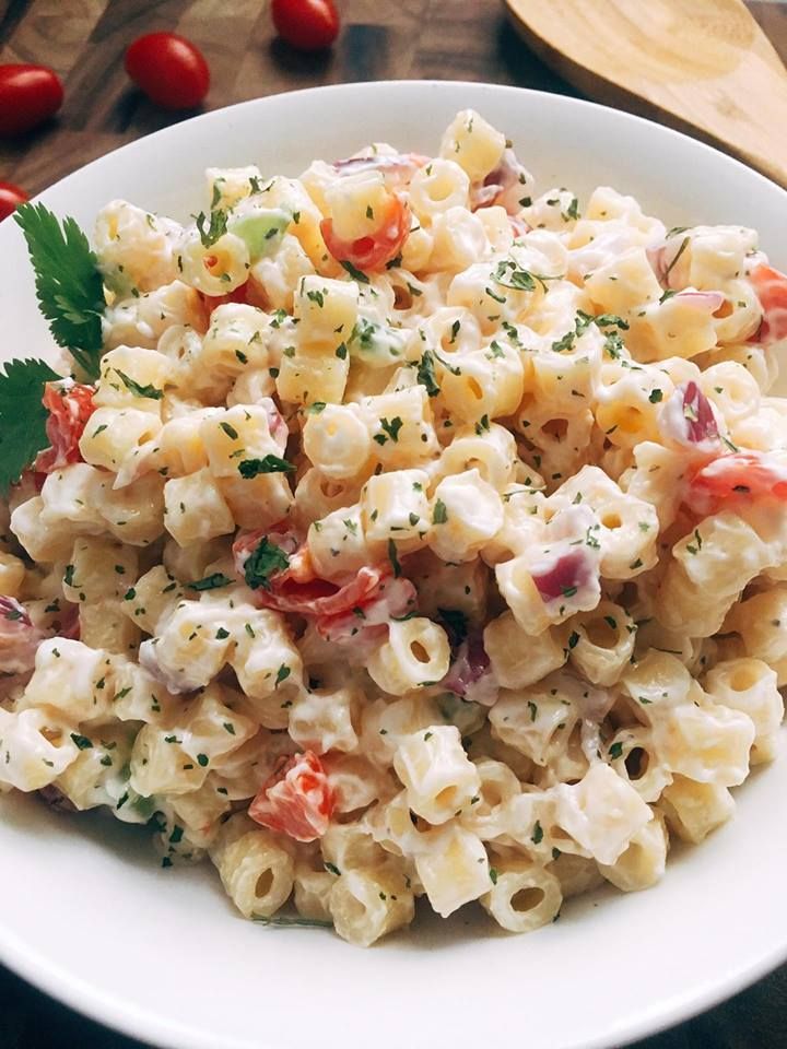 a white bowl filled with macaroni salad and garnished with parsley