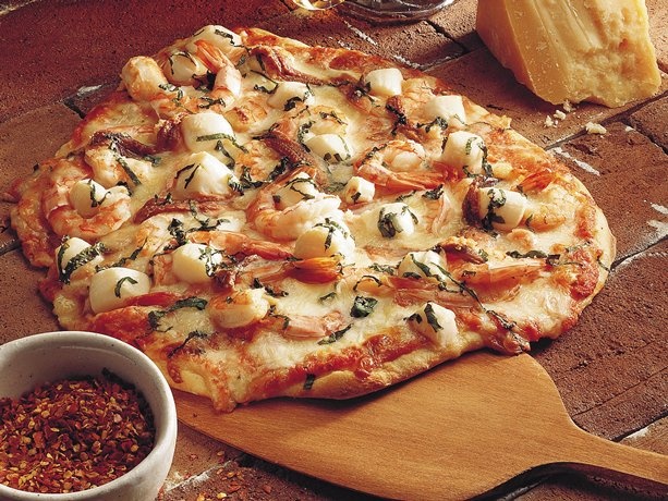 a pizza sitting on top of a wooden cutting board next to a bowl of sauce