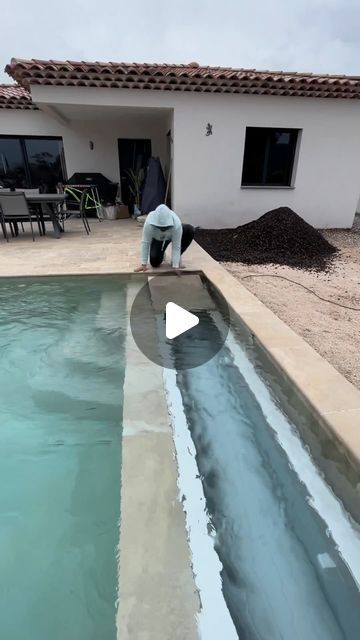 a man is standing in front of a pool with water coming out of it and sand on the ground