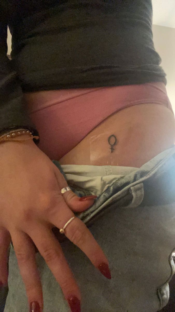 a woman's stomach with an anchor tattoo on her left side, and a ring in the middle