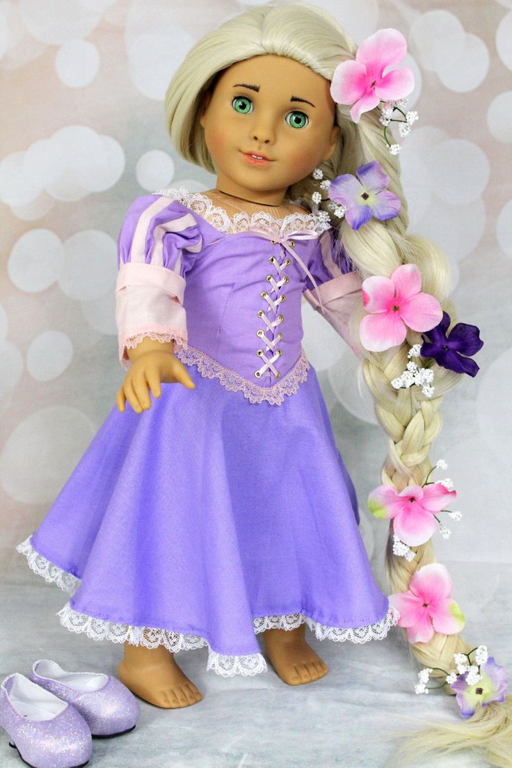 a doll with long blonde hair wearing a purple dress and holding a flower in her hand