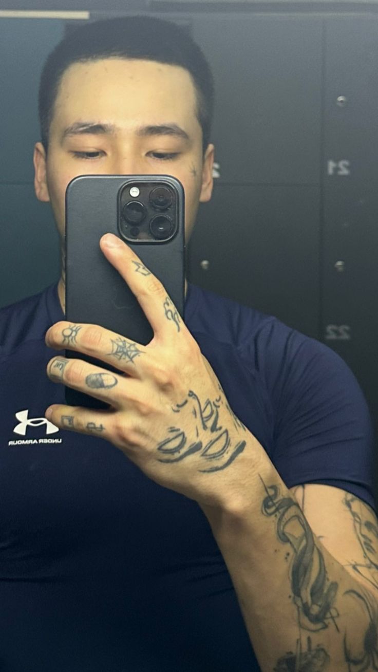 a man taking a selfie in front of a mirror with tattoos on his arms