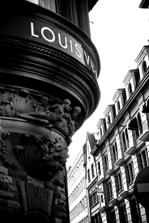 an old fashioned sign on the side of a building in paris, with buildings behind it