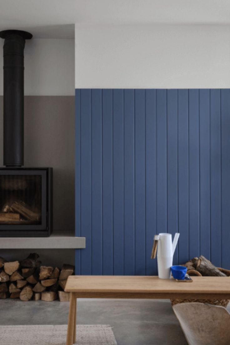 a living room with blue walls and wood burning in the fireplace, next to a coffee table