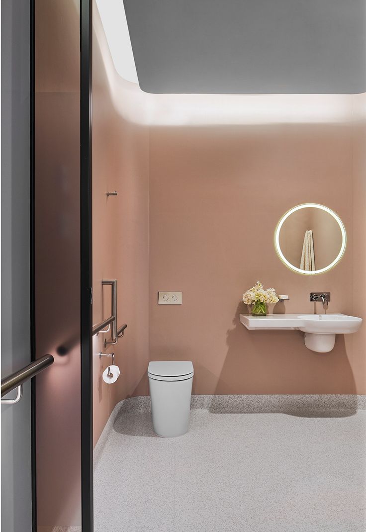 a bathroom with a toilet, sink and mirror in it's center wall is shown