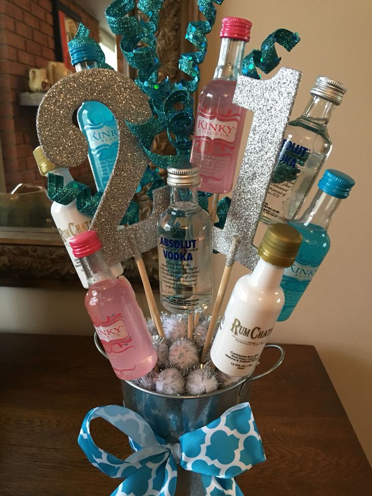 a vase filled with lots of different types of bottles and liquors on top of a table