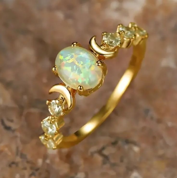 an opal and diamond ring sitting on top of a rock