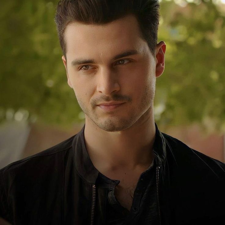 a close up of a person wearing a black shirt and a tree in the background