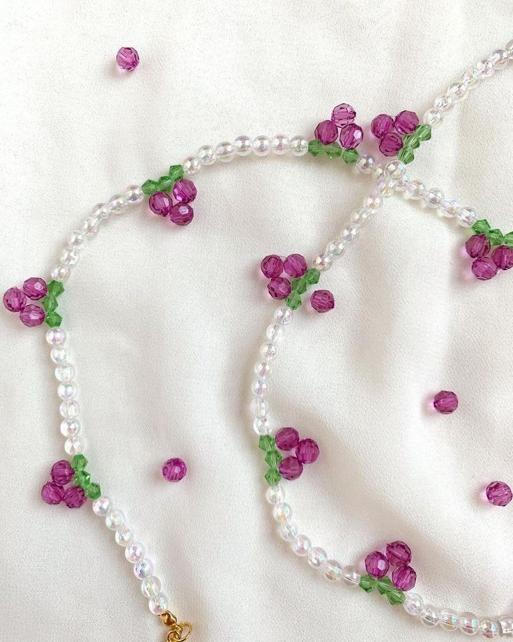 a necklace with beads and flowers on it sitting on a white cloth covered tablecloth