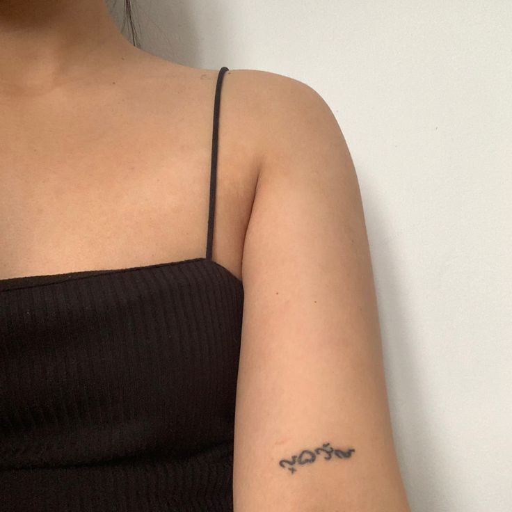 a woman with a small tattoo on her left arm and the word love written in cursive writing