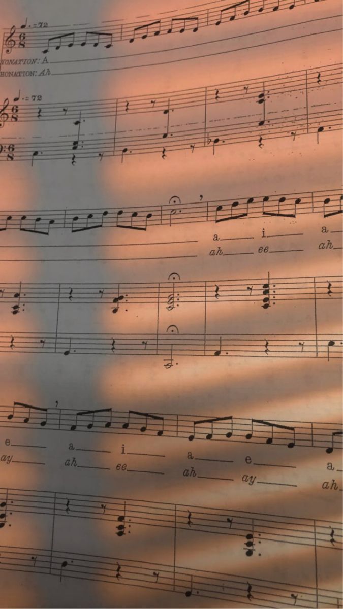 an image of sheet music with the sun shining on it and someone's shadow in the background