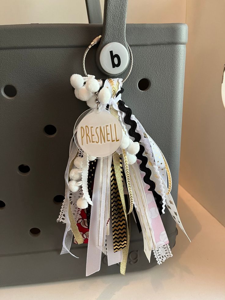 a bunch of ribbons are hanging from a bag handle with the letter b on it