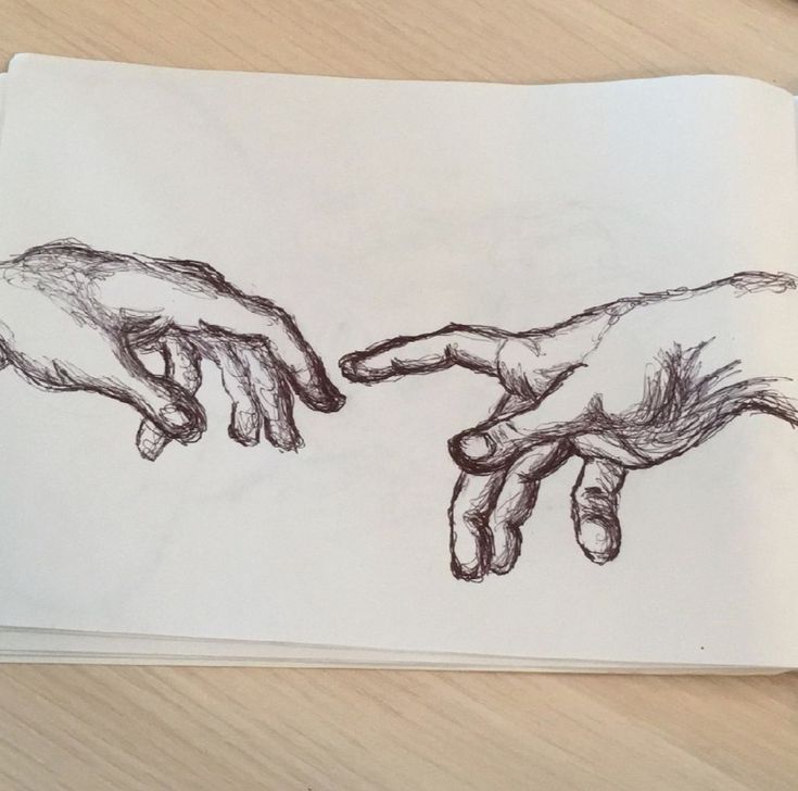 a drawing of two hands touching each other over a piece of paper on a table