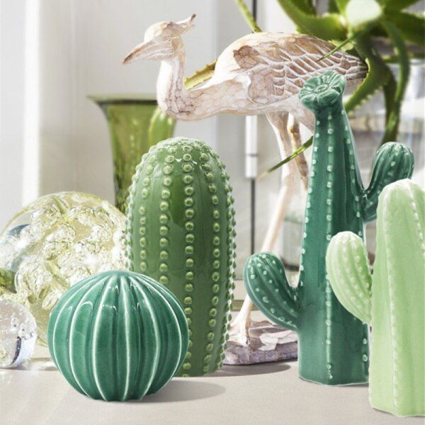 cactuses, cacti and other decorative items are arranged on a table in front of a potted plant