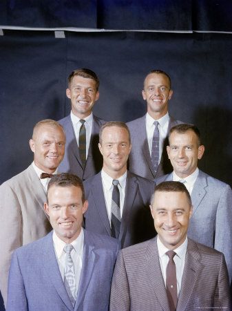 a group of men standing next to each other wearing suits and ties with one man smiling at the camera