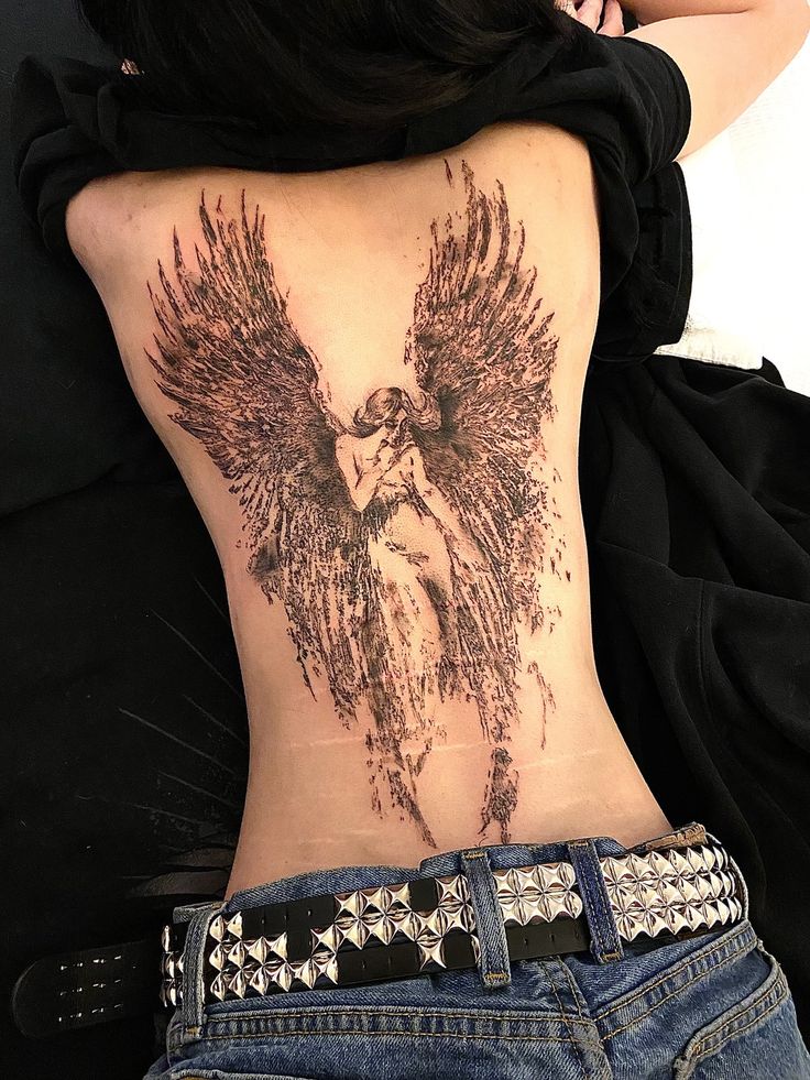 the back of a woman's stomach with an angel tattoo on her lower back