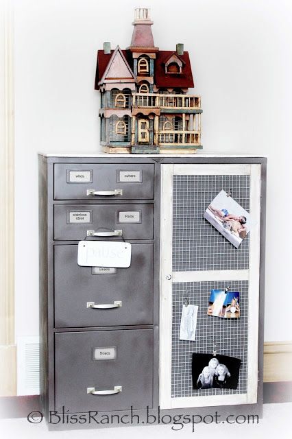 a gray filing cabinet with pictures on it and a doll house in the top shelf