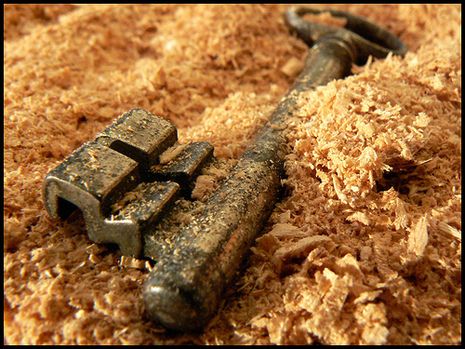 an old rusty key laying on top of wood shavings