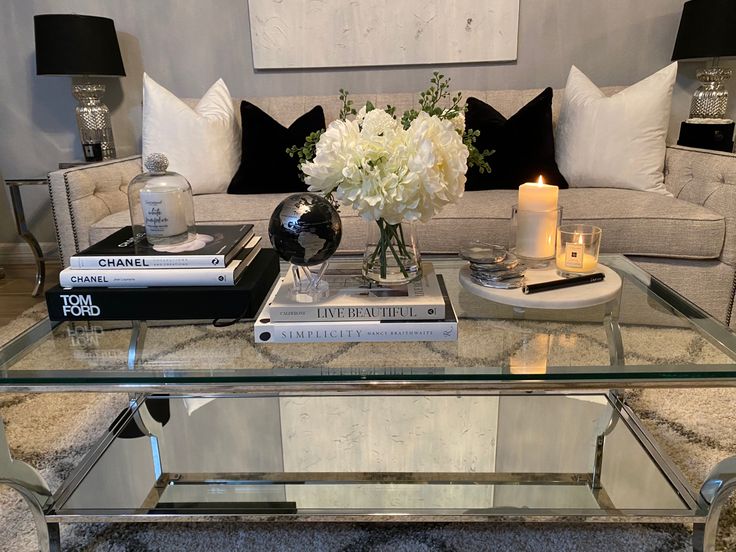 a glass coffee table topped with books and flowers