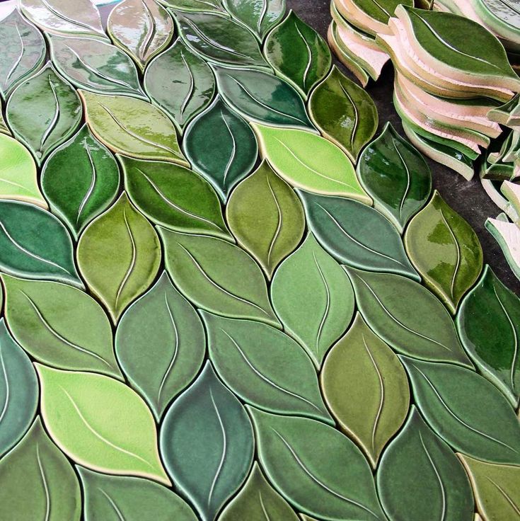 some green leaves are laying on top of each other in this artistic tile work design