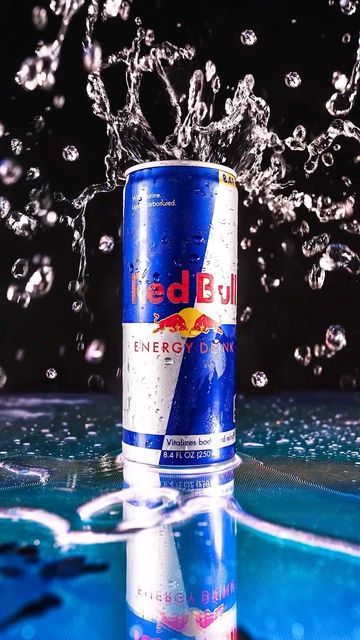 a can of red bull is splashing in the water