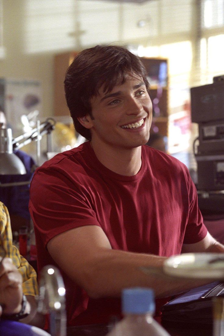 a young man smiles while sitting at a table with other people in front of him