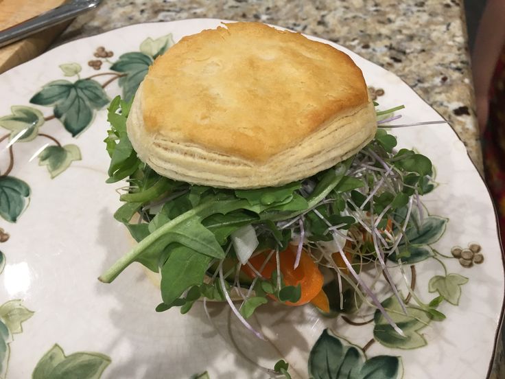 a plate with a sandwich on top of it and some leaves around the rims