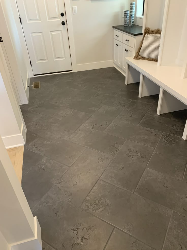 a room with white furniture and gray tile flooring in it's entry way