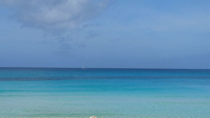 two people sitting on the beach with their surfboards in front of blue ocean water