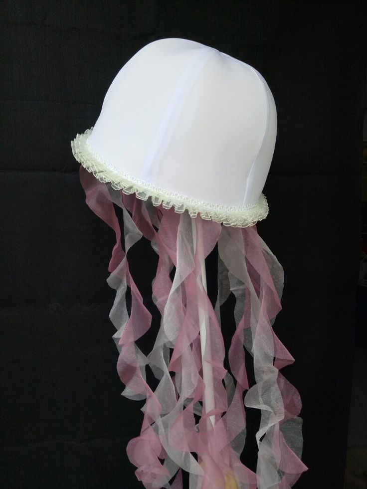 a white hat with pink ribbons hanging from it's side on a black background