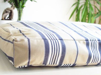 a blue and white striped pillow sitting on top of a table next to potted plants