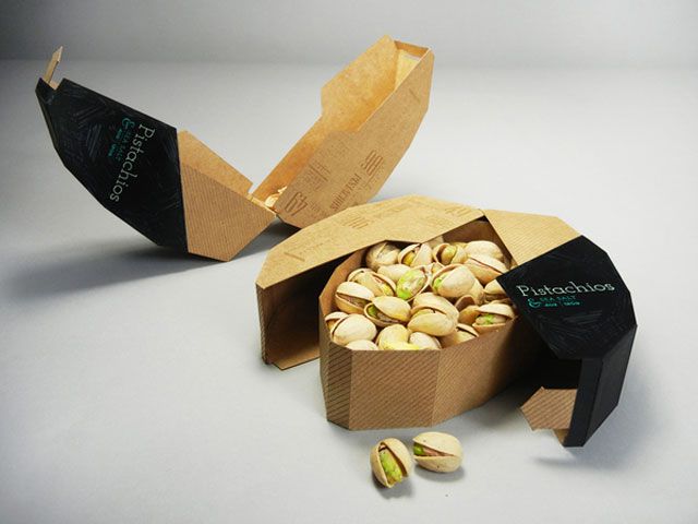 an open cardboard box filled with nuts on top of a white table next to a paper bag