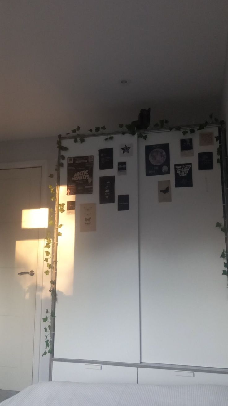 a bedroom with two white refrigerators covered in plants and pictures on the wall behind them