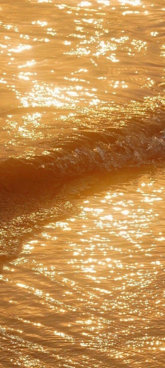 a man riding a wave on top of a surfboard in the ocean at sunset