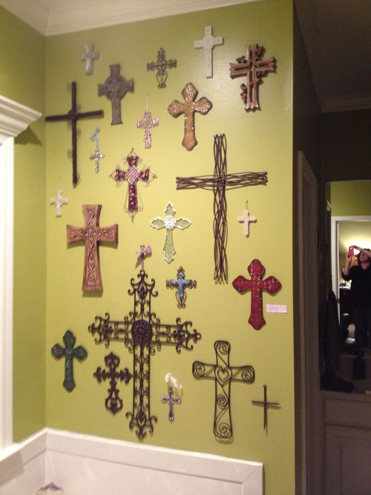 a wall with many crosses on it and people looking at the mirror in the background