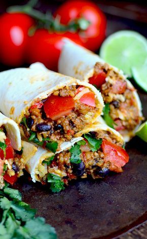 two burritos on a plate with tomatoes and cilantro