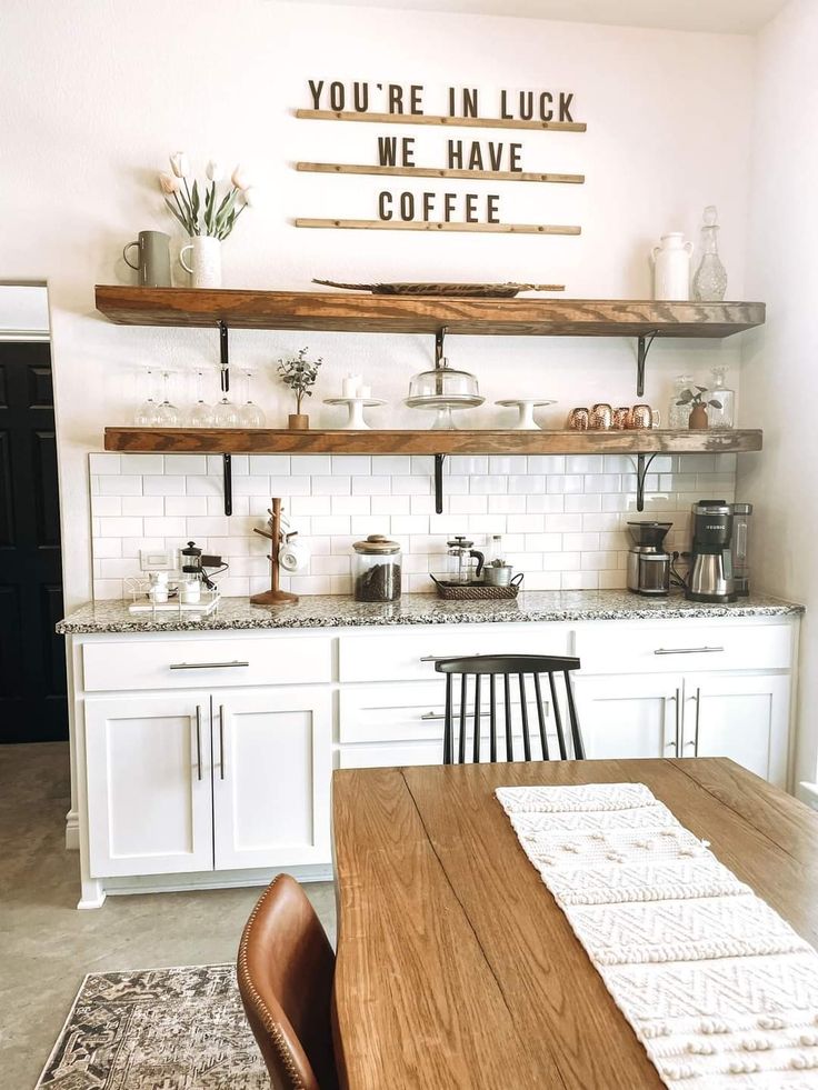 there is a wooden table and chairs in the kitchen with shelves above it that say you're in luck we have coffee