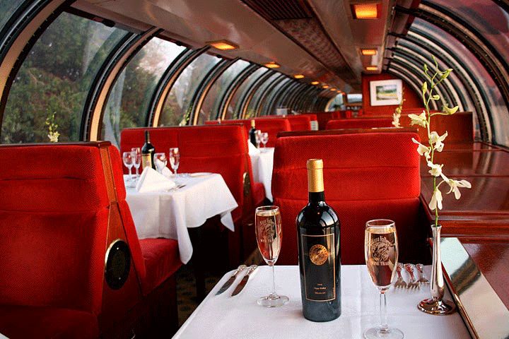 two wine glasses on a table in a restaurant with red booths and white tablescloths