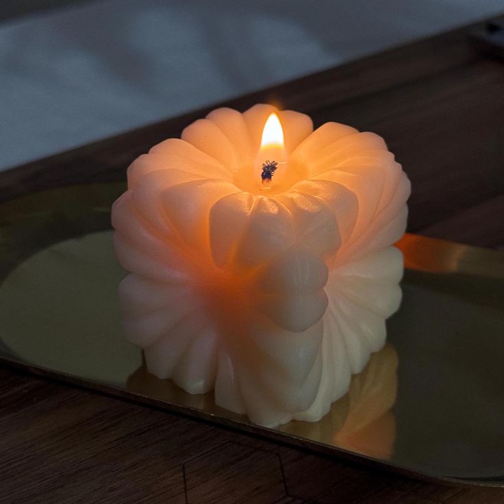 a lit candle sitting on top of a glass table next to a mirror with reflection