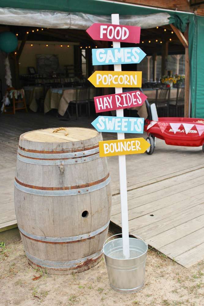 a wooden barrel sitting next to a sign that says food games popcorn hay rides water bouncer