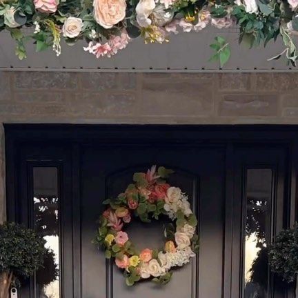 the front door is decorated with flowers and greenery