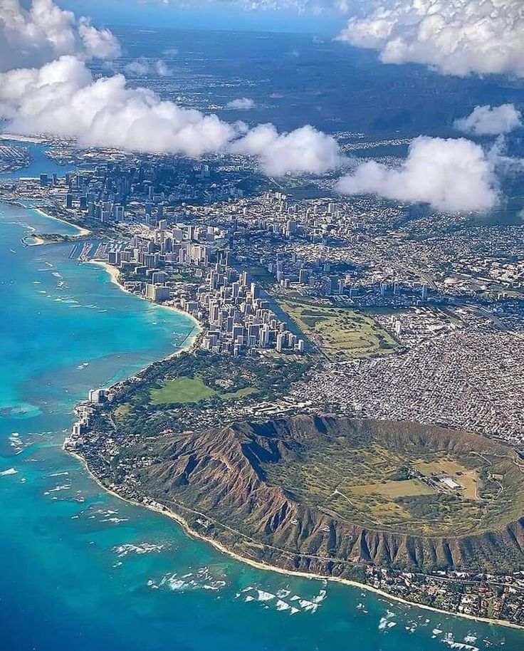 an aerial view of the city and ocean from above, with clouds in the sky