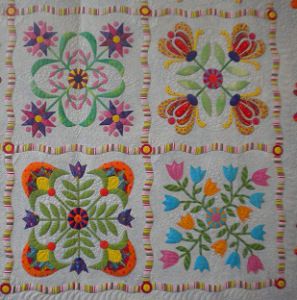 a quilted wall hanging with colorful flowers and leaves on it's sides,