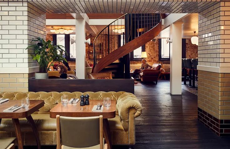 the interior of a restaurant with tables, chairs and couches in front of a staircase