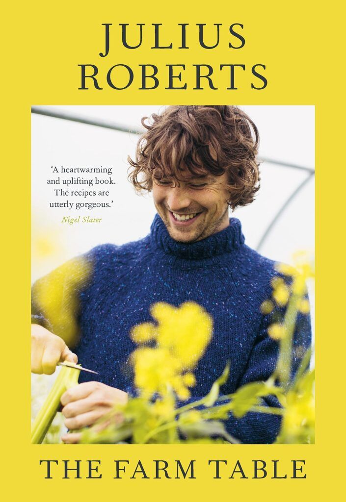 the farm table book cover with a man smiling and holding a plant in his hand