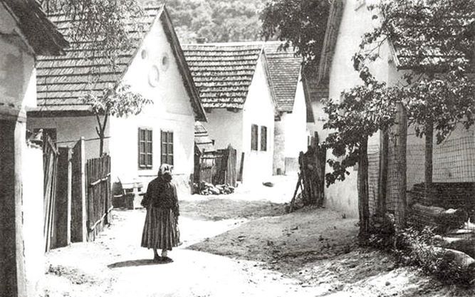 an old black and white photo of a woman walking down the street in front of houses